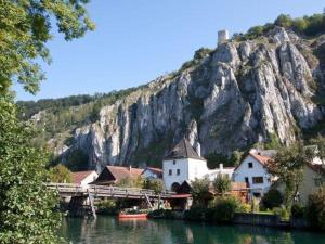 a village on a river with a mountain in the background at Ferienwohnung Leit'n Heisl in Essing