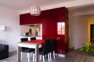 uma sala de jantar com uma parede vermelha e uma mesa e cadeiras em Baía dos Golfinhos Horta em Horta