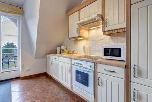 eine Küche mit weißen Schränken und einer Mikrowelle in der Unterkunft Haus Ostseeglück - Ferienwohnung Morgensonne mit Gemeinschaftssauna in Loddin