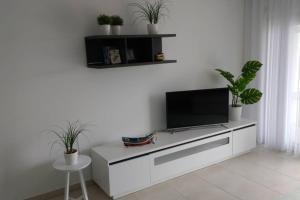 sala de estar con TV en una pared blanca en Gino´s House, en Nazaré