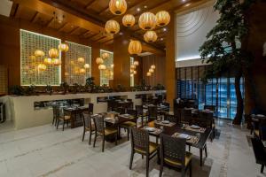uma sala de jantar com mesas, cadeiras e lustres em Asiana Hotel Dubai no Dubai