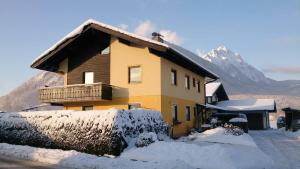 a house covered in snow with mountains in the background at Ferienwohnung Gabi in Piding