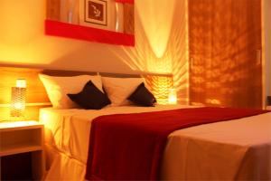 a bedroom with a bed with a red blanket at Assay Plaza Hotel in Hortolândia