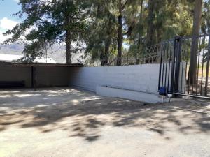 a fence in front of a white wall with trees at Escape in Prince Alfreds Hamlet
