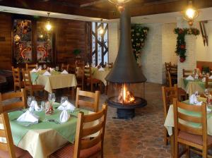 a restaurant with a fireplace in the middle of a dining room at Eco Complex Sherba in Debelets
