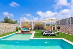 un patio trasero con piscina y sombrilla en Blue Mare Villa Rethimno, en Néa Magnisía