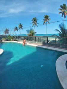 a woman in a swimming pool with the ocean in the background at Flat em Hotel de Luxo beira mar da grife Ritz suítes com vista ampla para todo o mar da cruz das almas, jatiúca e ponta verde, com toda estrutura de um hotel lindo e arrojado, academia, piscina e muito mais, venha viver essa experiência incrível! in Maceió