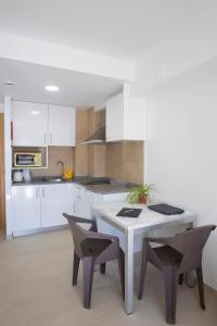 a kitchen with white cabinets and a table and chairs at Aparthotel BCL Levante Club in Benidorm