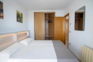 a bedroom with a white bed and a mirror at Aparthotel BCL Levante Club in Benidorm