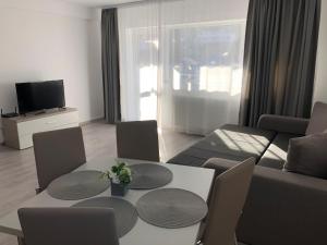 a living room with a couch and a table and chairs at Elena-Maria Apartments in Buşteni