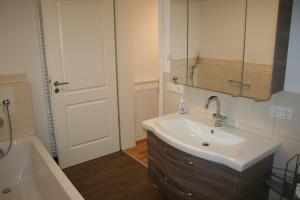ein Badezimmer mit einem Waschbecken, einem Spiegel und einer Badewanne in der Unterkunft Haus "Bergblick" Apartment mit 1 Schlafzimmer in Oberstaufen