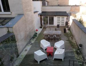 an outdoor patio with a table and white chairs at Villa Les Paquerettes in Ostend