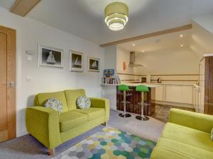 a living room with a green couch and a kitchen at The Old Auction Rooms in Whitby