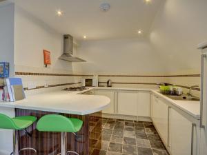 a kitchen with white cabinets and green bar stools at The Old Auction Rooms Lot 2 Central with Private Parking in Whitby