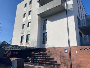 a white building with a brick wall next to it at JAB Apartament Przy Klinice Business & Family in Szczecin