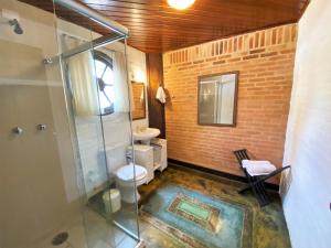 a bathroom with a toilet and a glass shower at Pousada do Sino in Campos do Jordão