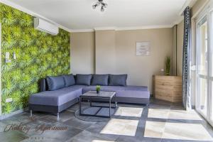 sala de estar con sofá púrpura y mesa en Kökény Apartman Bogács, en Bogács