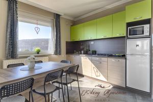 a kitchen with green cabinets and a table and chairs at Kökény Apartman Bogács in Bogács