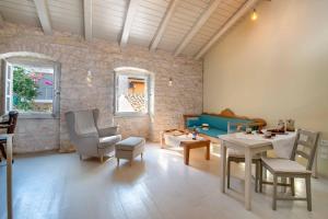 ein Wohnzimmer mit einem Tisch, Stühlen und einer Steinmauer in der Unterkunft Lakka Stone House 1 in Gaios