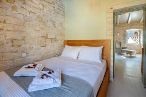 1 dormitorio con 1 cama con toallas y pared de piedra en Lakka Stone House 1, en Gáios
