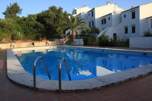 a swimming pool with blue water in front of a building at Gerry&Lotti Apartment in Son Bou