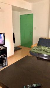 een woonkamer met een groene deur en een tv bij Luminoso departamento en el corazón de Olivos in Olivos