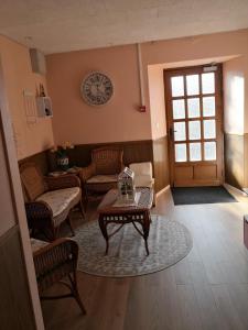 a living room with a table and a clock on the wall at La Ruche Cantalienne in Saint-Étienne-de-Chomeil +5 photos