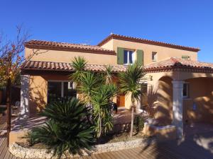 a house with palm trees in front of it at Maison Les Pins in Aigues-Mortes