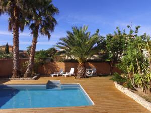 a swimming pool in a yard with palm trees at Maison Les Pins in Aigues-Mortes