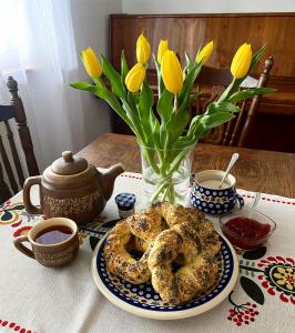 una mesa con un plato de pretzels y un jarrón con flores amarillas en ZACISZE, en Karłów