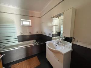 y baño con lavabo, espejo y bañera. en casa das Termas do Carvalhal, en Carvalhal