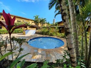 a swimming pool in a garden with a palm tree at Casa em Camburi in Camburi