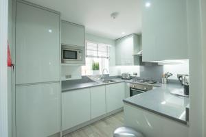 a white kitchen with white cabinets and a microwave at Headley House in Reading