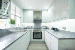 a kitchen with white cabinets and a stove top oven at Headley House in Reading