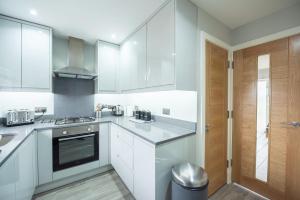 a kitchen with white cabinets and a wooden door at Headley House in Reading