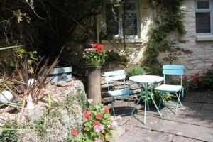 a patio with a table and chairs and flowers at The Little Acorn in Lydney