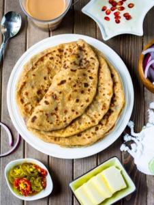 talerz chleba naan na stole z masłem i innym jedzeniem w obiekcie Tanish Homestay w mieście Bharbharia