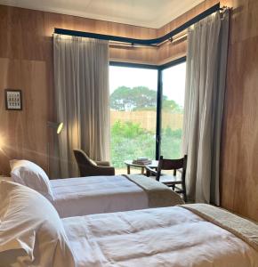 una camera d'albergo con due letti e una finestra di Rizoma a José Ignacio