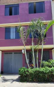 利馬的住宿－EL TUMI - Aeropuerto，一座紫色的建筑,前面有两棵棕榈树