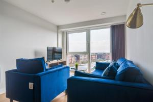 a living room with blue furniture and a large window at Lovely Riverside 2 Bed Apartment in Leeds
