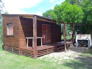 a small wooden cabin with a porch and a tree at • Cabaña Las Hortensias • in La Pedrera