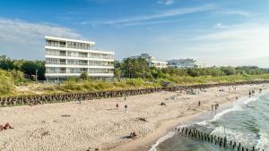 Leute am Strand mit einem Gebäude im Hintergrund in der Unterkunft Dune Beach Luxury Suites in Mielno