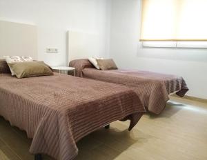 twee bedden in een kamer met een raam bij APARTAMENTOS MAITE in Peñíscola