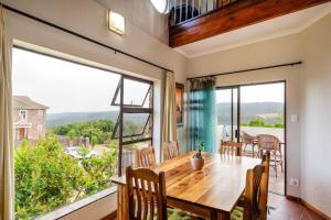 a dining room with a table and a large window at Agape holiday house in Herolds Bay