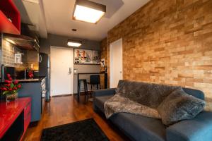 a living room with a couch and a brick wall at Rosemari's Apartments Sao Joao in São Paulo