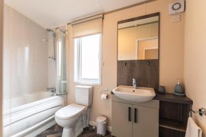 a bathroom with a white toilet and a sink at Springwell Lodge With Hot Tub in Malton
