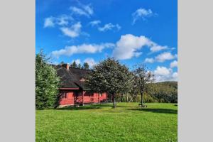 czerwona stodoła na zielonym polu z drzewem w obiekcie Znam Ten Widok - Bieszczady w mieście Ustrzyki Dolne