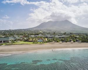 Four Seasons Resort Nevis في نيفيس: اطلالة جوية على شاطئ فيه جبل في الخلفية
