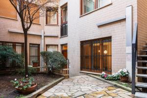 a brick building with a tree and a stone walkway at SPAZIO M&M CELLINI 3 in Milan