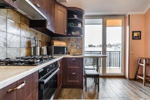 uma cozinha com armários de madeira e um forno com placa de fogão em Apartments “U prawnika” em Lviv